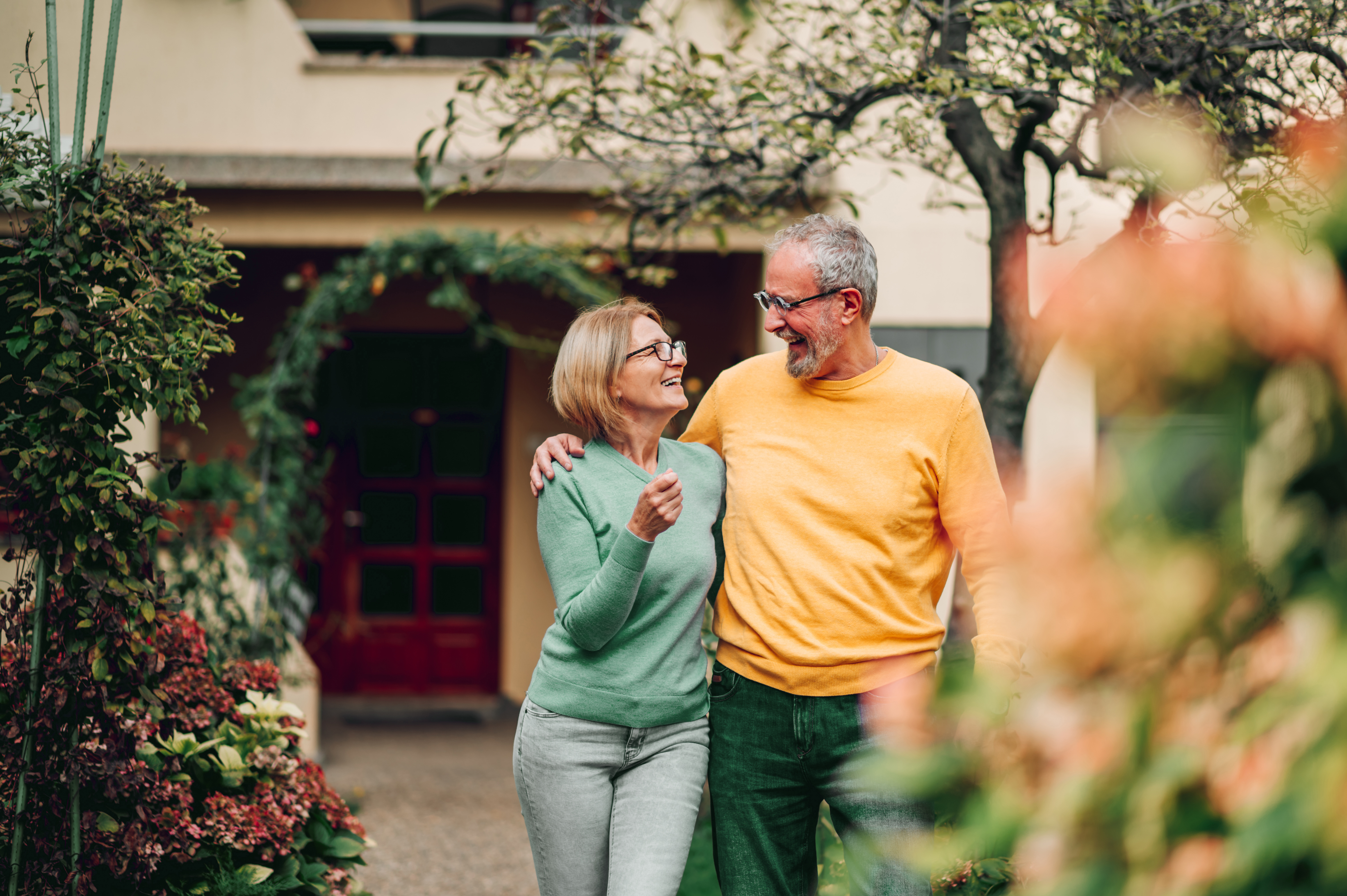 Smiling couple walking outdoors with trees in the background.